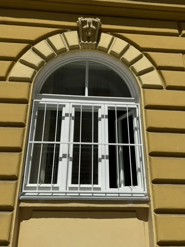 Bílá oblouková špaletová okna na historickém domě